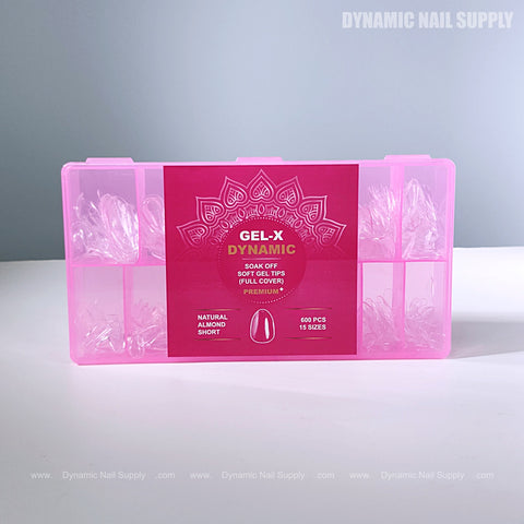 A pink box labeled Natural Almond (Short) holds clear, almond-shaped full cover soft-gel nail tips in compartments.