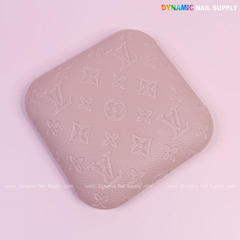 A beige square LV-engraved PU leather elbow pad pillow for nail techs, supportive and comfy for long hours.