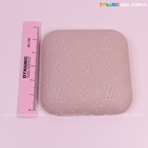 A pink ruler beside a Neutral Skin Color LV Engrave Elbow Pad Pillow for Nail Tech on a light pink surface.