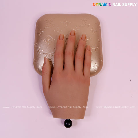 A Metallic Gold LV Engrave Elbow Rest Pillow for Nail Tech sits by a realistic mannequin hand and nail lamp.