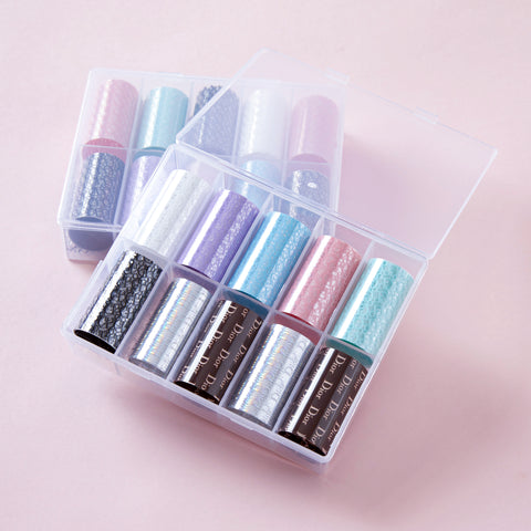 Two clear boxes hold Nail Art Design Foils - Luxury Style, arranged neatly on a soft pink background.