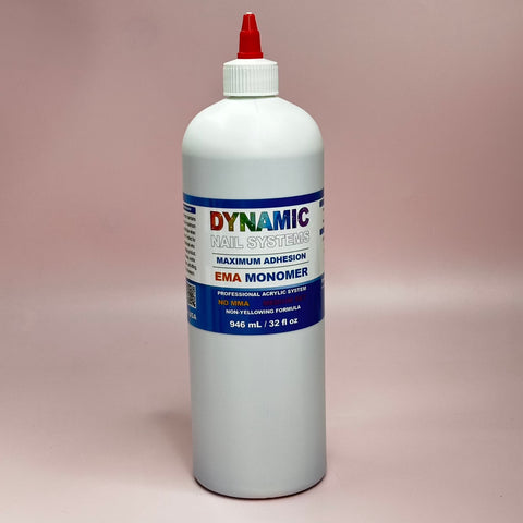A 946 ml (32 fl oz) white plastic bottle of Dynamic Nail Supply's EMA Nail Liquid Monomer features a red capped nozzle. The label highlights Maximum Adhesion and No MMA in bold text on a soft pink background, making it perfect for use with acrylic powder.