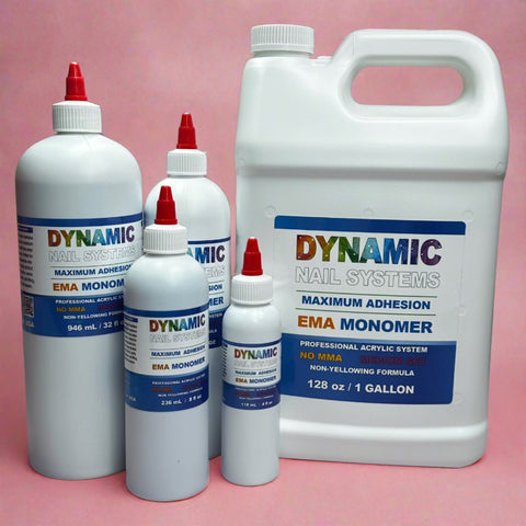 Five bottles of different sizes, all branded as Dynamic Nail Supply, are showcased against a pink background. The largest is a 1-gallon jug, accompanied by smaller containers, each capped with red-tipped lids. The labels emphasize features such as MAXIMUM ADHESION and the EMA Nail Liquid Monomer for a Non-Yellowing Formula, promoting the Healthier Nail Liquid Monomer from Dynamic Nail System.