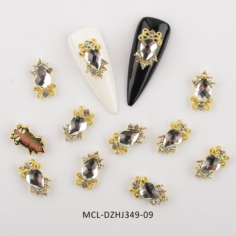 Dynamic Nail Supply offers a 20-piece collection of uniquely shaped charms designed for nail art enthusiasts. The set includes teardrop-shaped, faceted metallic gems adorned with small gold and silver embellishments. It's perfect for nail designers, featuring one black and one white decorated nail, along with a unique brown and gold piece. Product Code: MCL-DZHJ349-09.