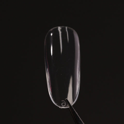 A Natural Round (Medium) Full Cover Soft-Gel Nail Tip held by tweezers against a plain black background.
