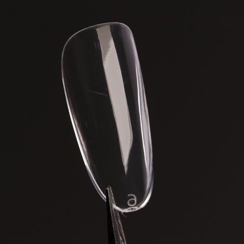 A Natural Round (Medium) Full Cover Soft-Gel Nail Tip is held upright by tweezers against a solid black background.
