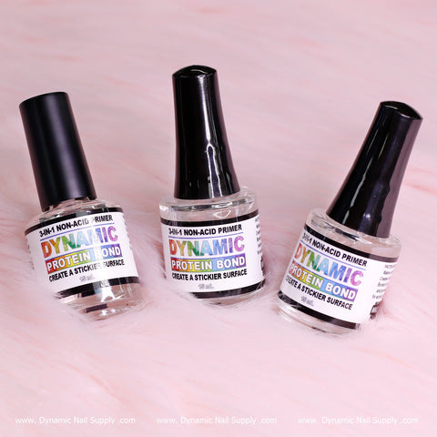 Three bottles of DYNAMIC PROTEIN BOND - Professional Non-acid Bonding for Preps from Dynamic Nail Supply are elegantly displayed on a soft pink surface. Each bottle has a black cap and a vibrant label that reads, "Create a Stickier Surface to Prevent Lifting Nails." For more details, visit www.DynamicNailSupply.com.
