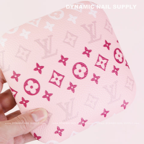 A hand holds the (RA018) Elbow Armrest for Nail Technicians in pink with Louis Vuitton-inspired monogram patterns.