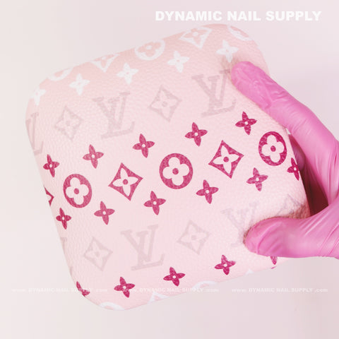 A pink-gloved hand holds the (RA018) Elbow Armrest for Nail Technicians against a light pink background.