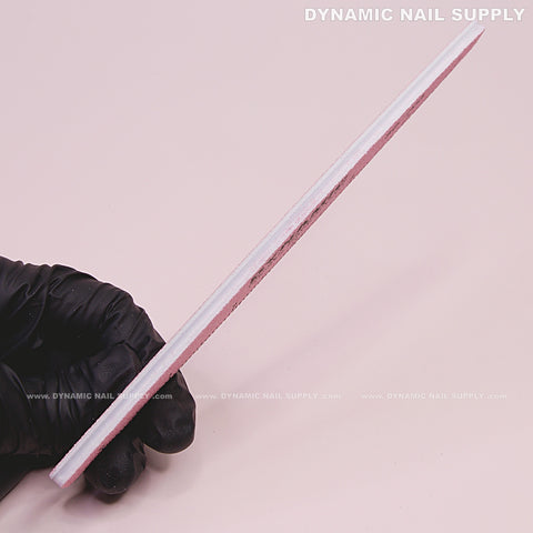 A gloved hand holds a Square Nail File 80/80 Grit, Pink, Double-sided from a 10-pack against a plain background.