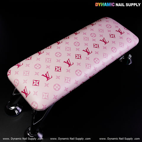 Pink armrest for nail table with shiny metal legs, red and white LV-style patterns.