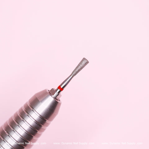 A close-up of a silver, cylindrical drill bit designed for fine Russian manicures, featuring a textured, pointed tip ideal for cleaning the cuticle area. Set against a pink background, the tip includes a thin red band at its base. The lower edge displays a subtle white text watermark that reads "Dynamic Nail Supply.