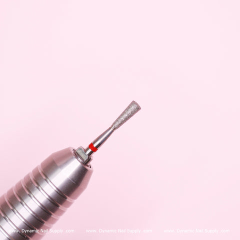 Close-up of a Dynamic Nail Supply Cylinder-shaped Drill Bit on a light pink background. Ideal for prepping and cleaning the cuticle area, this fine bit is marked with a small red ring near its base to indicate its non-abrasive coarseness. The softly blurred background accentuates the drill bit's details.