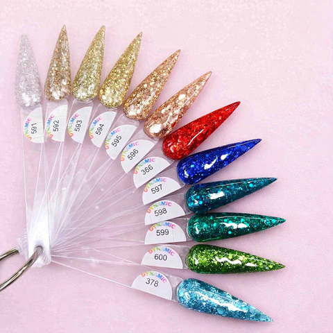 Ten long, pointed nails in glittery shades from the Holiday Sparkle Acrylic Powder Collection on pink background.