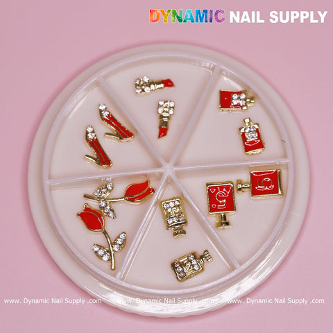 The product is a 12-piece set of Valentine's nail charms from Dynamic Nail Supply, featuring lipstick shapes, shoes, and red and gold perfume bottles. The round container with six compartments also includes sparkling flower designs. Set against a pink background, it has a white lid labeled with the brand name—ideal for nail designers.