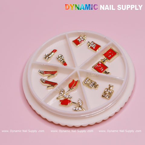 A circular container featuring six sections is set against a pink backdrop, highlighting the 12 pcs Valentines Nail charms for designer from Dynamic Nail Supply. These charms include red high heels, perfume bottles, roses, and handbags designed with gold and rhinestones—ideal for nail designers. The brand name Dynamic Nail Supply appears at the top right corner.