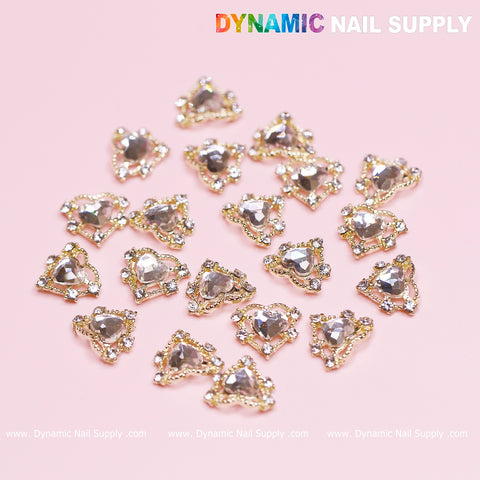A set of 20 luxury heart charms for Valentine nail designs featuring rhinestone border edges and gold accents, elegantly showcased on a pink background. The Dynamic Nail Supply brand is prominently displayed in the top right corner, highlighting their exquisite charm collection.