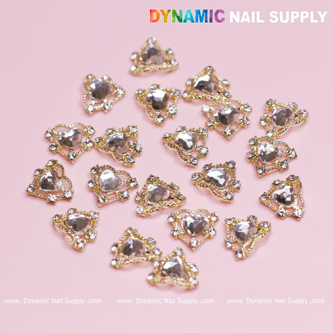 Introducing the 20 pcs Luxury Heart Charm for Valentine Nails Design by Dynamic Nail Supply: a stunning collection of heart charms featuring gold borders and rhinestone accents set against a pink background. These sparkling embellishments are perfect for creating intricate and eye-catching designs, arranged randomly to catch the light beautifully. The phrase "Dynamic Nail Supply" is prominently displayed at the top.