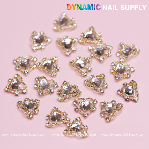 A set of nail art decorations featuring luxury heart charms with rhinestone borders and gold edges, randomly placed on a pink background. The design showcases "Dynamic Nail Supply" in bold white and colorful letters at the top right corner, embodying love and style.