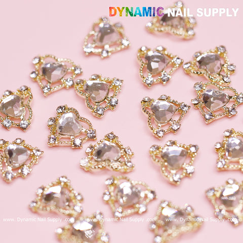 The 20-piece set of Luxury Heart Charm for Valentine Nails Design by Dynamic Nail Supply includes heart-shaped rhinestone charms with elegant gold settings. Each charm is embellished with a border of small, sparkling stones on its pink surface. The top showcases the Dynamic Nail Supply brand, and their website is displayed at the bottom.