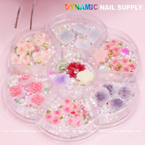 The 40 pcs White and Pink 3D 5D Rose Flower Charm with pearls from Dynamic Nail Supply offers a delightful selection of floral and pearl accessories, ideal for Valentine nails art designs. The set includes pink, purple, and white embellishments in each compartment, complete with tiny flowers and beads. Tweezers can be spotted in the top left corner for easy application.