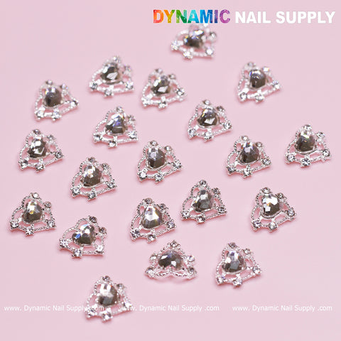 Rhinestone nail art, featuring reflective silver rhinestones elegantly arranged on a pink background, is complemented by smaller gems to form decorative clusters with the Silver Heart Charm from the 20 pcs Silver Heart Charm (Crystal heart Rhinestone) set. In the top right corner, the brand name Dynamic Nail Supply is displayed—ideal for creating Valentine Nails Design.