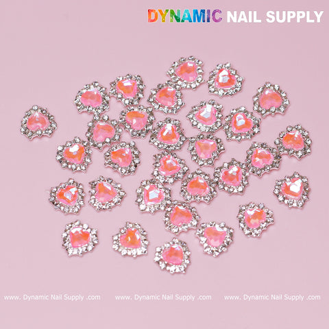 30 pcs 3D Pink Ruby Heart Rhinestone Nail Charms with pink stones and silver claw base on a pink background.