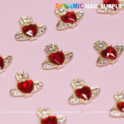 The captivating display showcases 12 pieces of Vivienne Westwood-style vintage red heart nail charms from Dynamic Nail Supply, each designed like a planet with clear rhinestone rings. These charming accessories rest against a soft pink background, adorned with the "DYNAMIC NAIL SUPPLY" watermark at the top of the image.