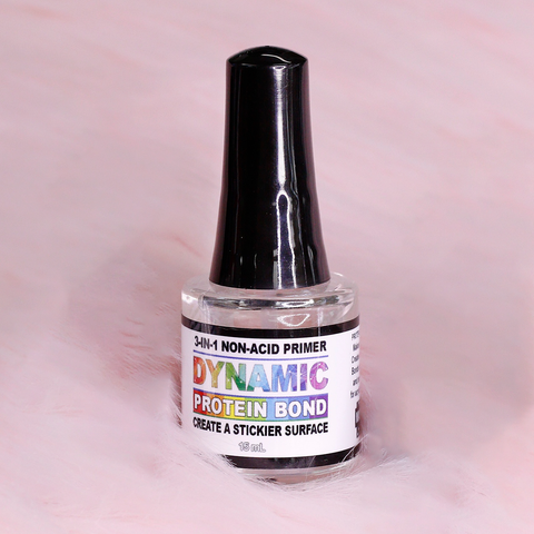 A bottle of Dynamic Nail Supply's DYNAMIC PROTEIN BOND - Professional Non-acid Bonding for Preps is highlighted against a soft pink background. The label, featuring rainbow gradient text, ensures prevention of lifting nails by creating a stickier surface. This clear, 15 mL bottle is topped with a black cap.