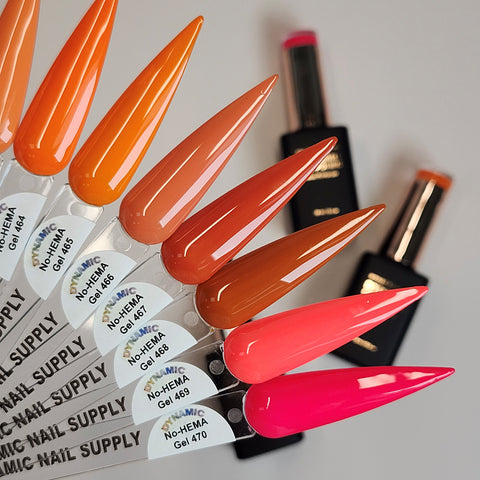 Six artificial nails in fall hues above two Dynamic No-HEMA Gel Polish bottles from the Fall Vibes Collection.