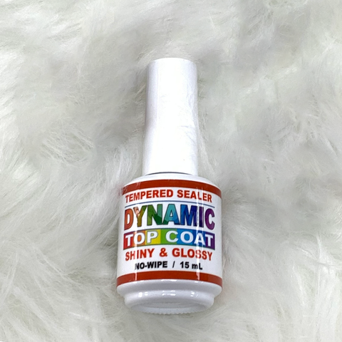 A bottle of nail polish labeled as Tempered Sealer and Shiny & Glossy, part of the Acrylic Nail Starter Kit by Dynamic Nail Supply, has a 15 ml capacity. Its label features colorful fonts, and the bottle is elegantly displayed on a textured surface resembling white fur.