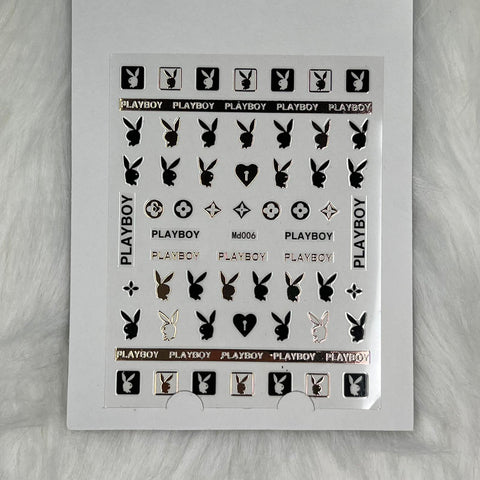 The Logo Sticker for Nails Art Design - md006 in RoseGold/Black by Dynamic Nail Supply features Playboy-themed nail stickers adorned with black, white, and rosegold Playboy bunny logos along with the word PLAYBOY in a variety of styles. These peel-and-apply stickers, showcasing both solid and outlined designs, are neatly arranged on a fluffy white background.