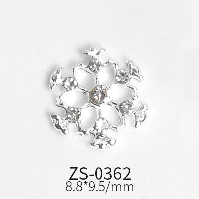 An elaborate snowflake charm in a silver finish, featuring detailed cutouts and small clear gemstones surrounding a larger central gemstone. From Dynamic Nail Supply's collection, this product is labeled as model ZS-0362 and accommodates various nail shapes, available in sets of 24 pieces. Dimensions are 8.8 x 9.5 mm.