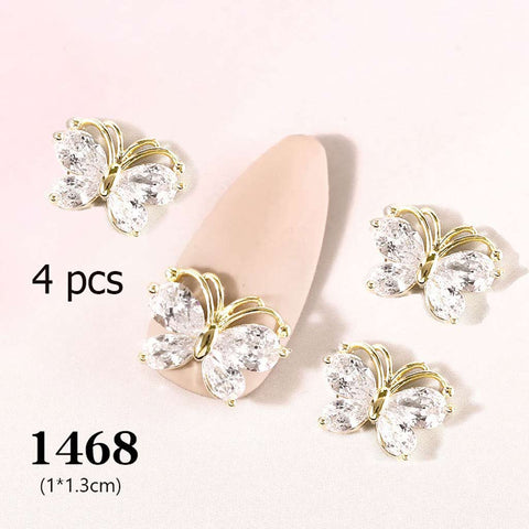 Four exquisite butterfly-shaped nail charms with white, gem-like wings are artfully arranged around a light pink nail tip on a white background. Text in the lower left corner reads "4 pcs 3D Butterfly Charm for Nails Art Design (code 1468)," showcasing these elegant additions from Dynamic Nail Supply.