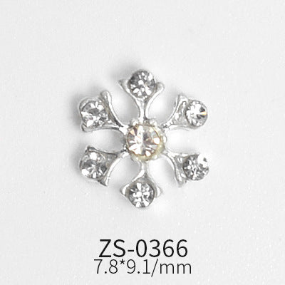 These snowflake charms, designed for winter and Christmas nail art, feature a stunning floral shape with six petals that resemble hearts. Each charm has a central gem surrounded by six smaller gems, making them perfect for enhancing your nail designs. Known as ZS-0366 and measuring 7.8*9.1 mm, this set of 24 pieces is available from Dynamic Nail Supply against a plain white backdrop.