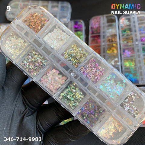 A hand in a black glove holds a clear plastic case filled with the NAIL DESIGN GLITTER 9 by Dynamic Nail Supply. The compartments are packed with iridescent, star-shaped sequins in vibrant colors. The brand name, Dynamic Nail Supply, and a phone number are elegantly printed on the image, capturing the essence of creative artistry.