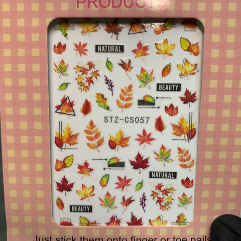 Dynamic Nail Supply's "FALL Nail Designs Stickers for Fall Season 2021" features vibrant autumn-themed stickers with maple and oak leaves in shades of red, orange, and yellow. Some designs include the words "NATURAL" and "BEAUTY," all set against a pink-and-white checkered background, with the code STZ-CS057 visible.