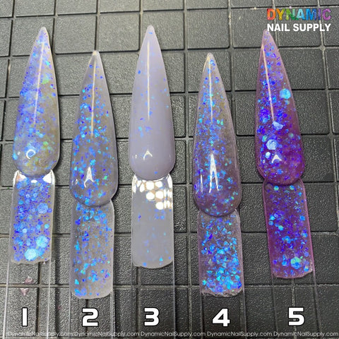 Five elongated stiletto nail samples are displayed against a textured black background, each showcasing different shades of purple enhanced by holographic glitter. Number 1 is pastel; 2 is clear; 3 features lavender; 4 merges purple and blue hues; and 5 stands out with vibrant purple created using the Explicit series - Dirty Sprite - Glitter Acrylic Powder Collection for sculpting and dipping nails. The Dynamic Nail Supply logo sits proudly in the top right corner.