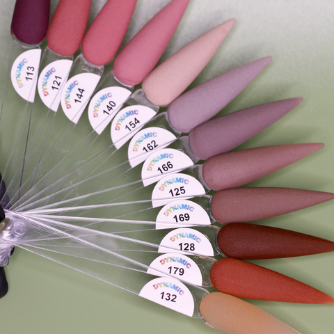 A fan of nail polish swatches in a range of matte colors, featuring shades like pink, mauve, and earthy tones. Each swatch is distinctly marked with a code number and Dynamic Nail Supply on a small sticker. The background showcases a light green gradient that highlights the 2024 Fall Acrylic Powder Collection (part 1) Brown and Dark shades, ensuring long-lasting nails.