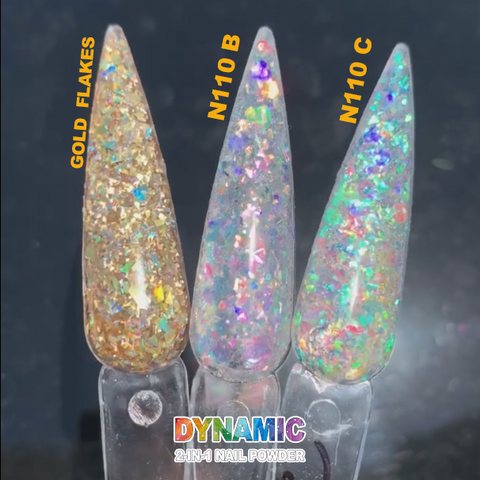 The dynamic display features three long, pointed nail designs, each highlighting unique holographic glitter effects. The left nail, Gold Flakes - Iridescent Flakes from Dynamic Nail Supply's Unicorn Flakes collection, shines with gold and multicolored glitter from our Non-toxic Dipping Powder. The middle nail captivates with the pink and blue tones of N110 B, while the right nail sparkles vibrantly with the multicolor brilliance of N110 C. Text reads Dynamic 2-in-1 Nail Powder.