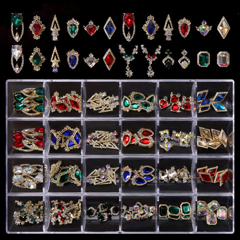A display case showcasing the "120 pcs Trending Nail Charms Set" from Dynamic Nail Supply holds 24 compartments, each brimming with colorful and sparkling nail art pieces set in golden settings. These exquisite treasures include vibrant crystal gems in red, blue, green, and iridescent hues against a striking black background.