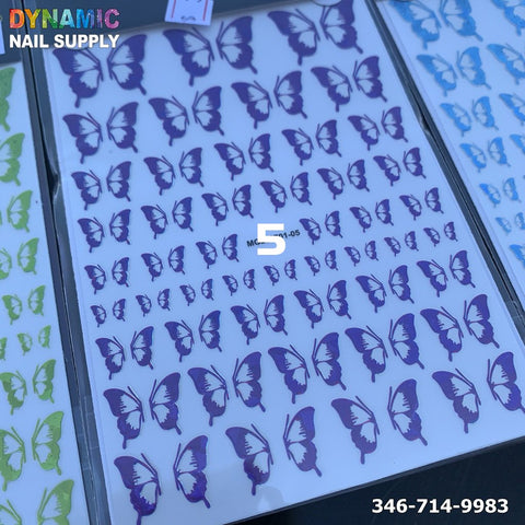 A sheet of Holographic Metallic Butterfly Stickers for Nail Art Design in various shades of purple, shimmering with a metallic allure, is displayed. The Dynamic Nail Supply brand is visible in the top left corner, while the phone number 346-714-9983 appears in the bottom right. Green and blue sheets of butterfly stickers are partially visible on either side.