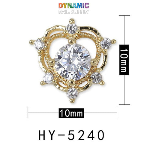 A luxurious jewelry element from Dynamic Nail Supply, specifically designed for nail art, measures 10mm by 10mm. Featuring a central large diamond encircled by an ornate gold design with six smaller diamonds, it embodies high-end nail decoration. The product name is Luxurious Jewelry for Nail Art Design and is labeled as HY-5240.