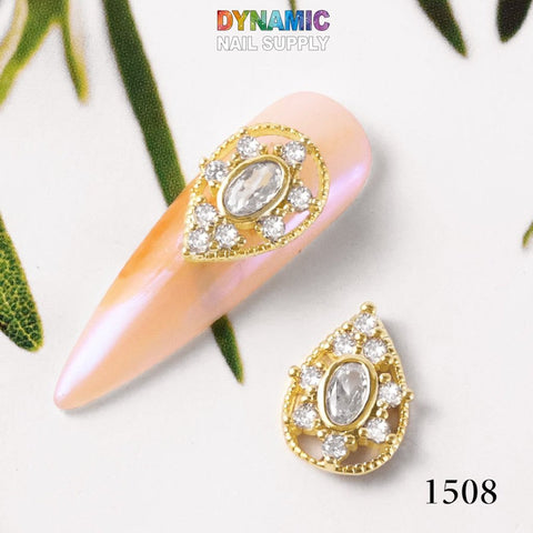 This luxurious jewelry-inspired nail art design from Dynamic Nail Supply, part of the "Luxurious Jewelry for Nail Art design - part 2" collection, features pink almond-shaped artificial nails adorned with gold accents and rhinestones. A centerpiece teardrop-shaped rhinestone is surrounded by smaller clear rhinestones and gold detailing, completed by the number 1508 and the Dynamic Nail Supply logo.