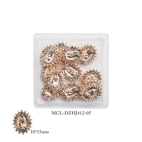 The square dish contains multiple oval-shaped Virgin Mary charms that feature intricate patterns, ideal for a religious nail design. These charms have a gold-tone base with sparkling accents along the edges. One charm, labeled 10*15mm and MCL-DZHJ412-05, is shown separately below. This product is available as a 12 pcs bag from Dynamic Nail Supply under the name (Small version) Virgin Mary charms for Religious nails design.