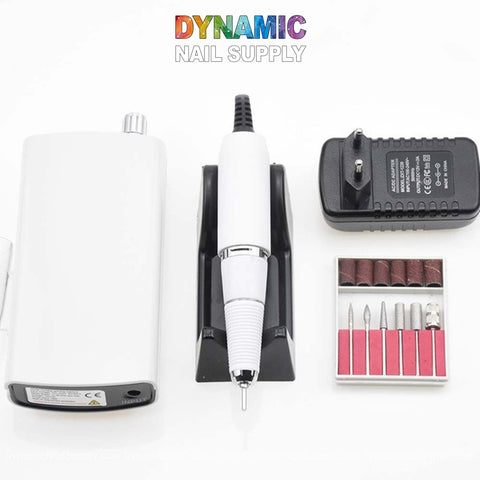 The Manicure Nail Drill Machine from Dynamic Nail Supply includes a white handpiece electric file on an elegant black stand, paired with a power adapter and control unit. It comes with various drill bits for precision in manicure nail drilling. The lively rainbow text is striking against the clean white background.