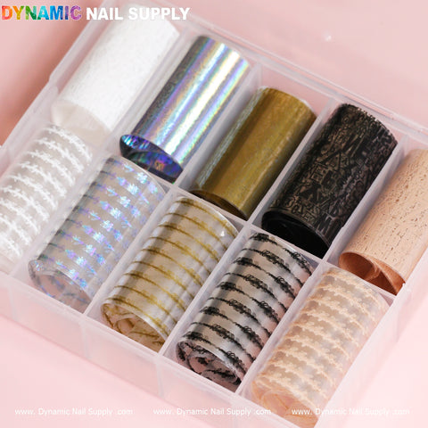 A plastic organizer filled with the Nail Art Design Foils - Letters Style from Dynamic Nail Supply contains ten rolls of nail art foil, displaying a variety of designs such as sparkly white, holographic silver, textured gold, and others. These captivating foils also include black and gold patterns, all under the distinguished branding of Dynamic Nail Supply.