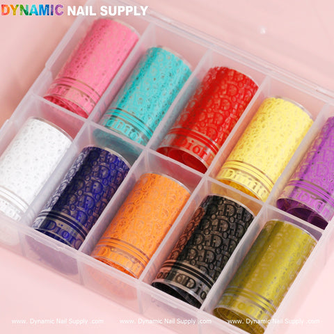 The Nail Art Design Foils - Luxury Style by Dynamic Nail Supply is an ideal clear plastic organizer for nail art enthusiasts, featuring 12 rolls of foils with luxury-style patterns in a variety of colors: white, light blue, red, green, beige, purple, orange, pink, yellow, black, gold, and silver. The rolls are tidily placed in individual compartments with the box lid open.