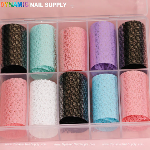 A plastic box containing ten rolls of Nail Art Design Foils - Luxury Style from Dynamic Nail Supply features intricate lace-like patterns in colors such as light blue, pink, white, purple, and black. Labeled at the top with the brand name Dynamic Nail Supply, this set is an ideal choice for anyone looking to enhance their nail art with a touch of luxury.