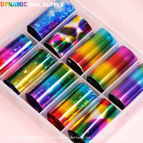 In a plastic organizer, the Nail Art Design Foils - Colorful by Dynamic Nail Supply feature ten vibrant holographic designs, including shades of blue, green, yellow, pink, and rainbow. These foils boast a glossy and reflective surface, displayed against a light pink backdrop with the brand name Dynamic Nail Supply visible in the image.